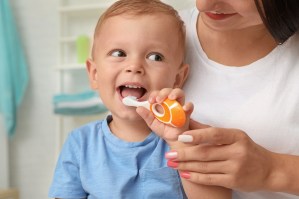 a woman helps a small child use a toothbrush