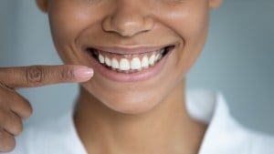 a smiling woman points at her mouth