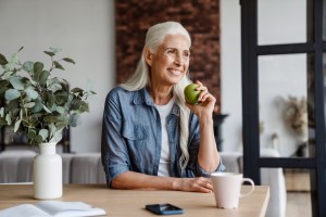 Older woman with healthy teeth eating and enjoying a green apple