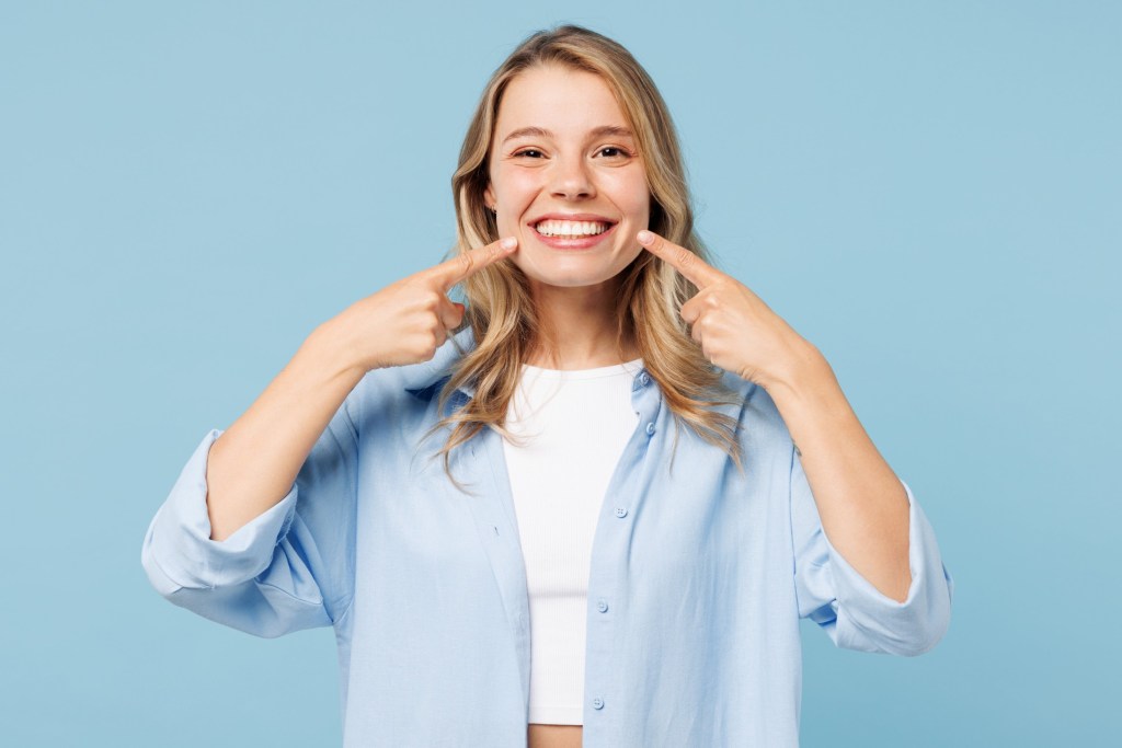 Young woman smiling pointing at teeth