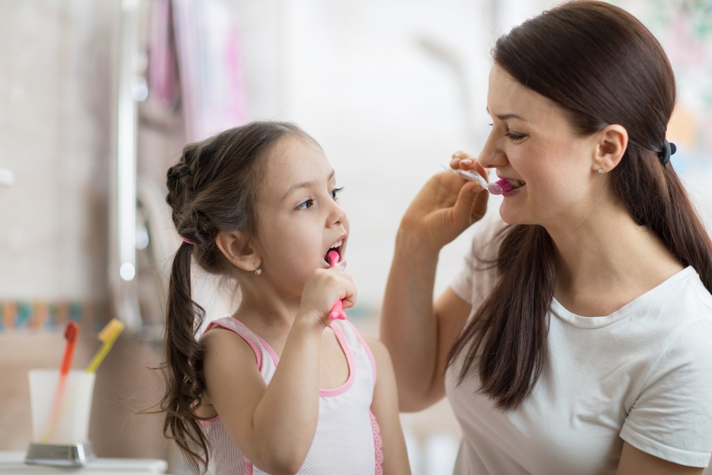 mother teaching kid daughter teeth brushing