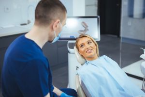 Dental patient in medical chair speaking with dentist